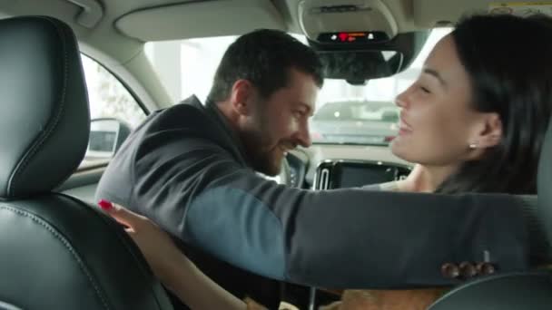 Медленное движение мужчины и женщины, обнимающихся внутри красивой новой машины в салоне — стоковое видео