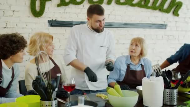 Muž kuchař v uniformě mluvit se skupinou lidí ve třídě vaření diskutovat o jídle — Stock video