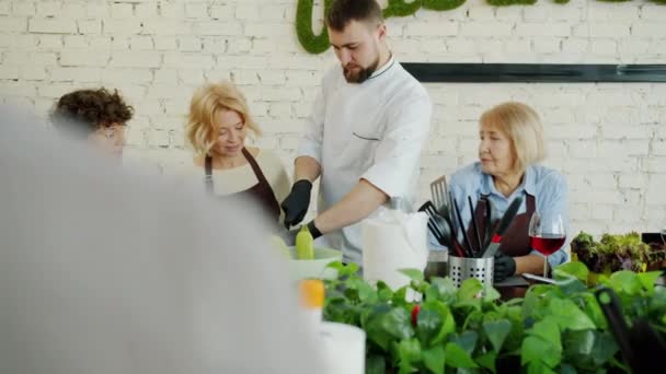 Profesora de clases de cocina picando comida enseñando a las mujeres en hermosa cocina — Vídeo de stock