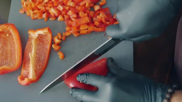 Vue du dessus des cuisiniers mains dans des gants hacher du poivre juteux dans la cuisine faire de la salade — Video