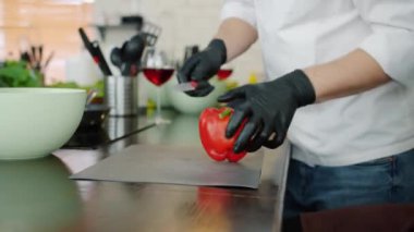Erkek eldiven giyip, mutfakta biber doğrayan salata yerken yakın plan.