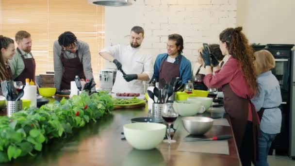 Grupo multiétnico de estudiantes de clases de cocina viendo cocinar haciendo comida — Vídeos de Stock
