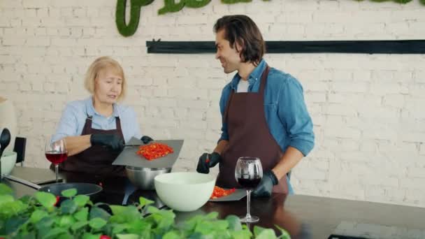 Donne e uomo in grembiuli che cucinano in cucina parlando durante la masterclass culinaria — Video Stock