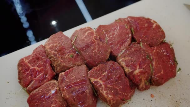 Крупный план кусочков свежего мяса на столе, готового к барбекю на кухне — стоковое видео