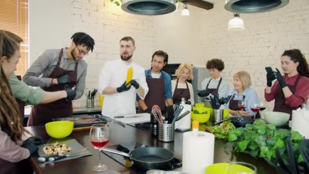 Estudiantes de la escuela de cocina y chef masculino cocinan platillo de carne juntos aprendiendo culinaria — Vídeo de stock