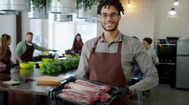 Aşçılık okulunda elinde kızartma tavasıyla yakışıklı Afro-Amerikalı bir adamın portresi.