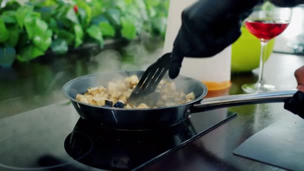 Mano en guante mezclando verduras picadas freír en la sartén en la cocina — Vídeos de Stock