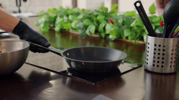 Movimento lento de pessoas mão na luva colocando legumes picados na frigideira — Vídeo de Stock