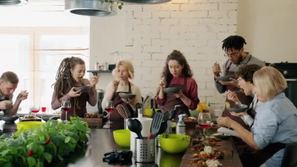 Diverse group of people enjoying delicious meal after cooking lesson in culinary school — Stock Video