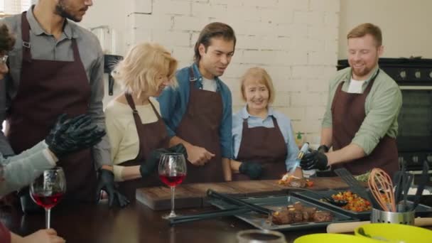 Trage beweging van kok maken schotel met open vuur terwijl culinaire scholieren applaudisseren — Stockvideo