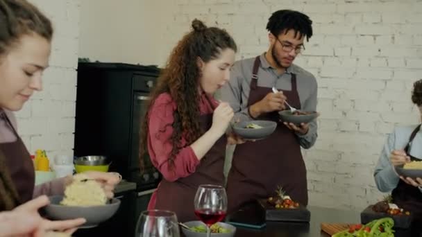 Groep gelukkige mannen en vrouwen die heerlijke maaltijden eten na culinaire masterclass — Stockvideo