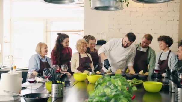 在厨房做饭和说话的学生的专业厨师教学小组 — 图库视频影像