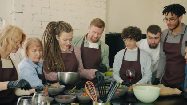 Gente feliz en delantales cocinando comidas disfrutando de la cocina master-class en interiores — Vídeo de stock