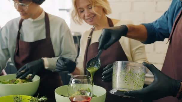 Skupina mužů a žen vaření nádobí ve třídě kuchařství práce společně těší koníček — Stock video