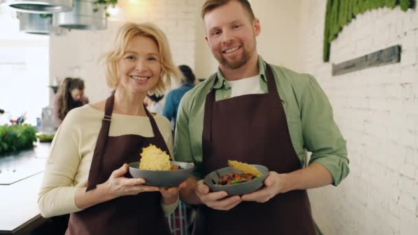 Portrait of man and woman holding dishes standing together in cookery school — Stock Video