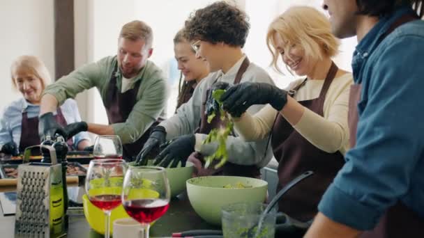 Diverse group of cooking class students making meals together talking in kitchen — Stock Video