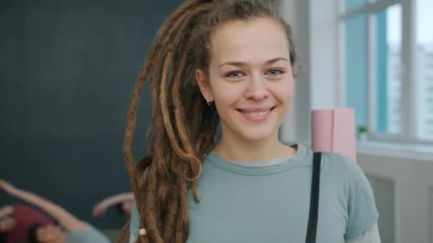 Портрет очаровательной молодой женщины-студентки йоги, стоящей в помещении в студии и улыбающейся — стоковое видео