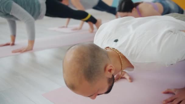 Alıştırma yapmaktan hoşlanan bir grup kadınla yoga yapan yakışıklı bir adam. — Stok video