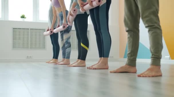 Geringe Aufnahme von Yoga-Studenten, die im Studio Matten ausrollen und dann barfuß gehen — Stockvideo