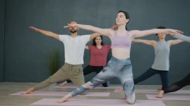 Spor merkezinde egzersiz yapan aktif gençler minderlerde yoga yapıyorlar.