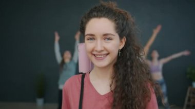 Çekici yoga hocasının portresi stüdyoda kameraya bakıp gülümsüyor.