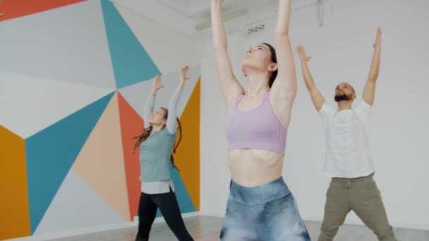 Homem sério e mulheres ocupadas com asanas ioga durante a aula no estúdio moderno — Vídeo de Stock