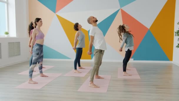 Lezione di yoga facendo curve all'indietro e in avanti che esercitano all'interno in studio di luce — Video Stock