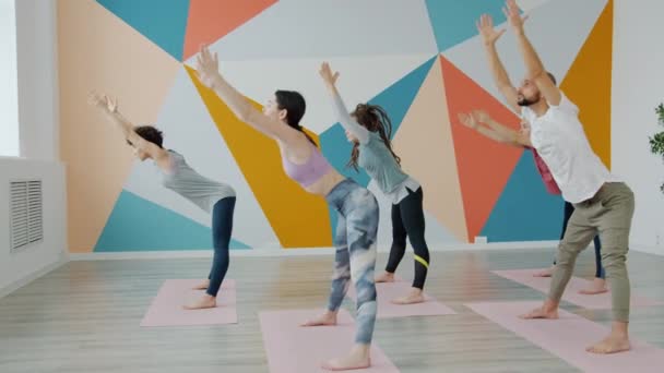 Grupo de jóvenes formados en estudio de yoga concentrados en doblar asana — Vídeos de Stock
