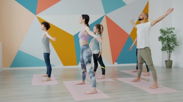 Flessibile giovani donne e uomo godendo di esercizi fisici durante la lezione di yoga — Video Stock