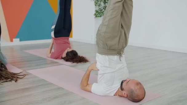 Клас йоги виконує зворотні вправи, лежачи на килимах з піднятими ногами, зосередженими на практиці. — стокове відео
