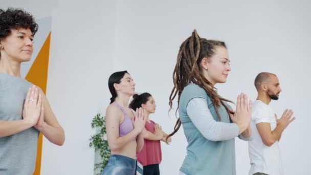 Lento movimiento de los estudiantes de yoga espirituales jóvenes haciendo ejercicios de equilibrio en estudio — Vídeos de Stock