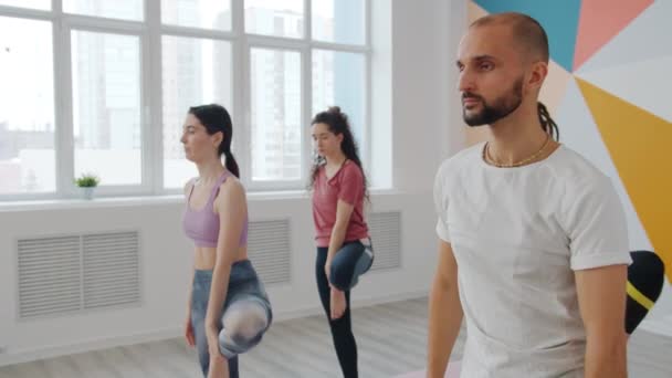 Poważne kobiety i mężczyzna korzystających relaks podczas jogi praktyki w centrum sportowym — Wideo stockowe