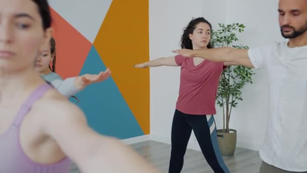 Giovani sani che praticano yoga al chiuso nel club sportivo piegando il corpo alzando le braccia — Video Stock