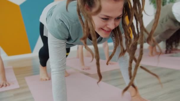 Yoga dersi sırasında spor salonunda bir grup insanla birlikte çalışan mutlu genç bir kadın. — Stok video
