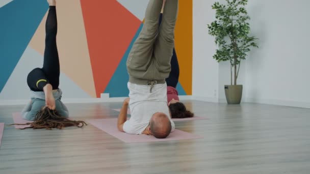 Groep van yoga studenten verhogen benen omhoog liggend op matten in studio oefenend omgekeerde positie — Stockvideo