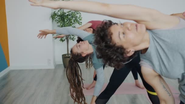 Yoga stüdyosunda kadın eğitmenle egzersiz yapan bir grup genç kız ve erkek. — Stok video
