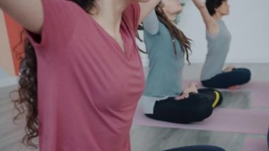 Yoga dersinde nilüfer pozisyonunda meditasyon yapan güzel genç kadınların ağır çekimleri.