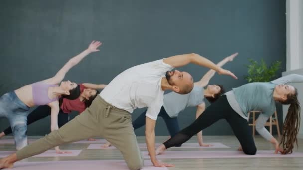 Yoga stüdyosunda spor yapan aktif erkek ve kadınlar vücut kaslarını esnetiyor. — Stok video
