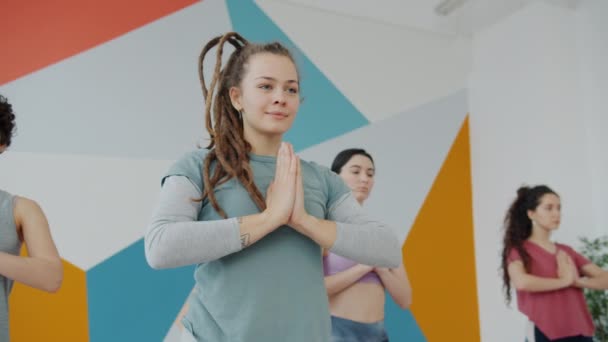 Веселая студентка йоги делает упражнения на равновесие, держа руки в намасте — стоковое видео