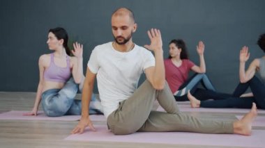 Bir grup yoga öğrencisi paspaslar üzerinde eğilme egzersizleri yapıyor.