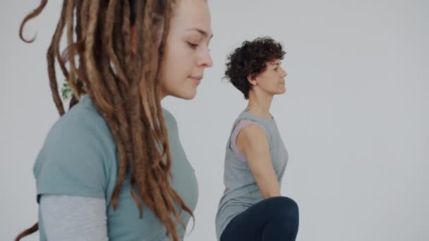 Grupo de mujeres jóvenes atractivas haciendo yoga en centro deportivo enfocado a la práctica en interiores — Vídeo de stock