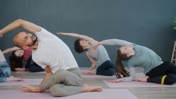 Långsam rörelse av yogaklassen gör Gomukhasana position vilar sedan med händerna i namaste — Stockvideo