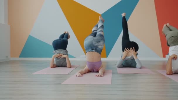 Yoga class πρακτική αντίστροφη asanas στο στούντιο για χαλάκια τέντωμα πόδια επάνω στο πάτωμα — Αρχείο Βίντεο