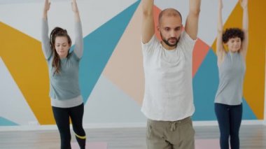 Genç çekici erkek ve kadınlar modern stüdyoda yoga asanası kompleksi yapıyorlar.