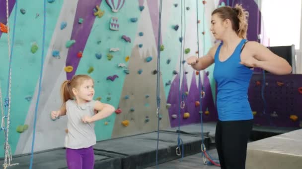 Movimiento lento del calentamiento de la madre y la hija antes de escalar la pared en el gimnasio interior — Vídeos de Stock