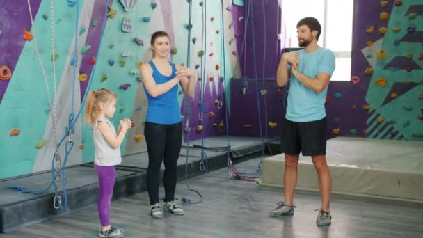 Joven familia madre, padre e hija calentamiento en el gimnasio de escalada juntos — Vídeos de Stock
