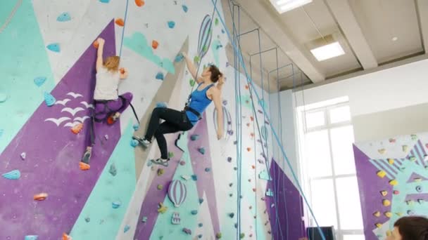 Kind en jonge dame klimmen binnen in sportcentrum wordt ondersteund door metgezellen — Stockvideo