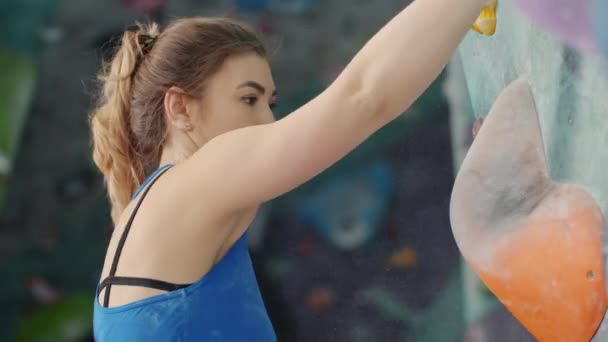 Mujer joven seria en traje deportivo escalando en interiores agarrando rocas brillantes — Vídeos de Stock