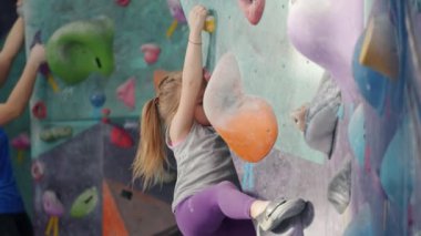 Ciddi bir çocuk, duvarda tırmanmaya odaklanmış.