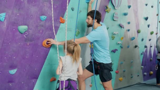 Padre e hija hablando en el gimnasio de escalada en roca listos para subir por la pared artificial — Vídeo de stock